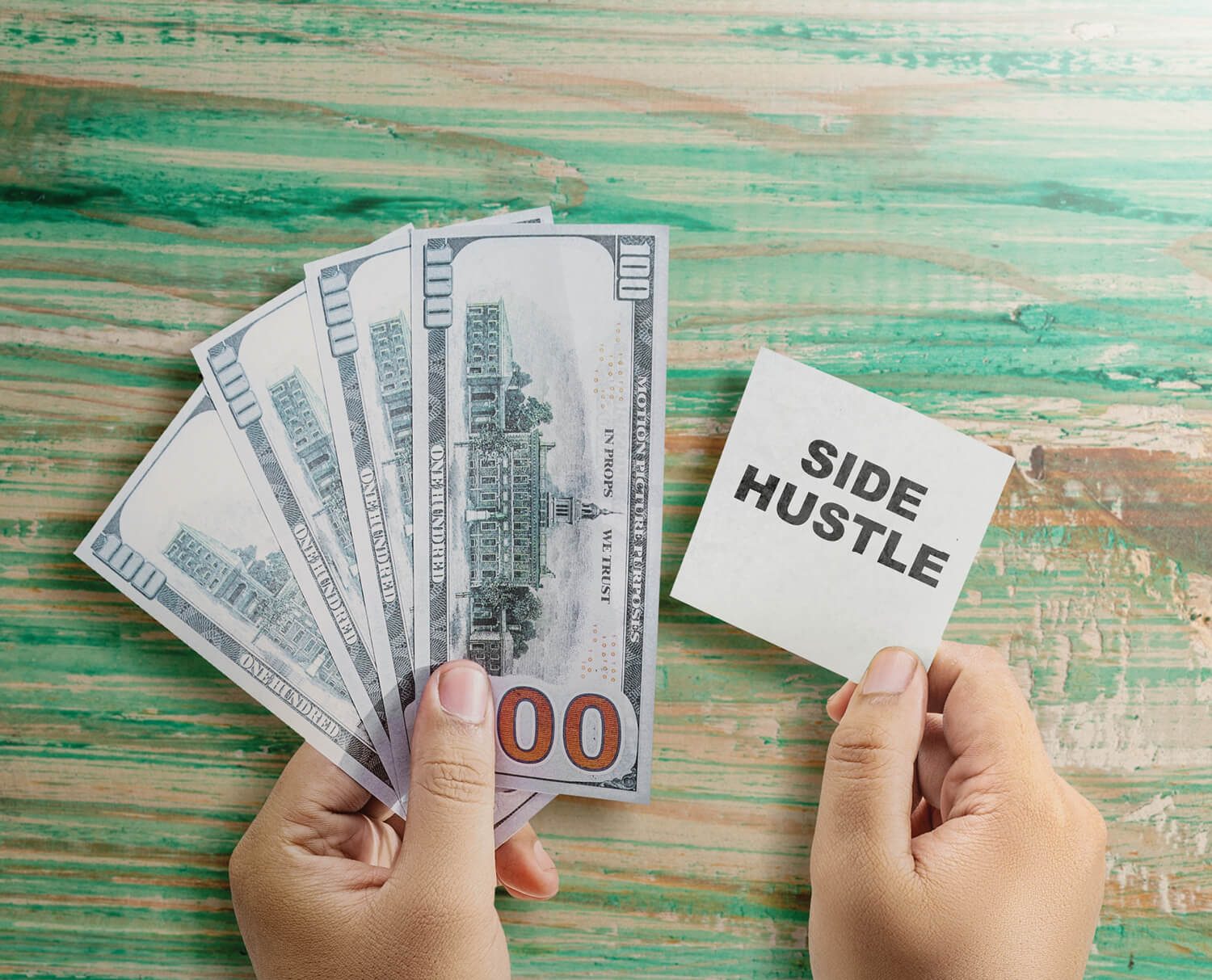 A man holding a stack of cash in one hand and a note reading “Side Hustle” in the other, representing extra income opportunities.