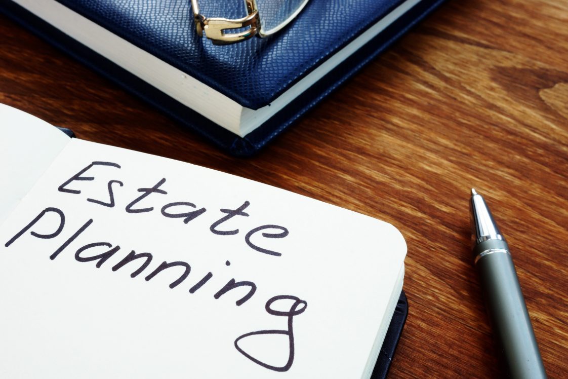The words “Estate Planning” written on a piece of paper beside a pen, symbolizing the start of organizing one’s financial legacy.