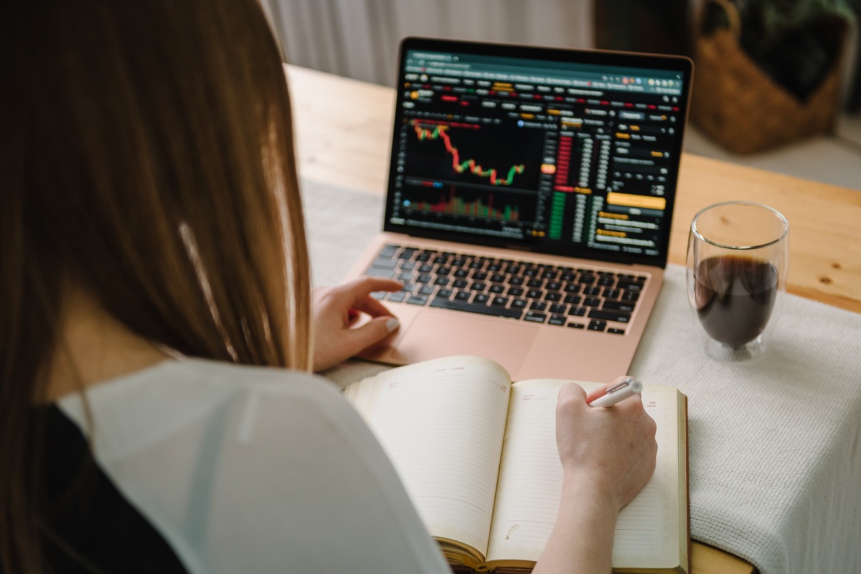 bull market trend. cryptocurrency. falling bitcoin stock. chart shows a strong fall in price of bitcoin. back top view. young girl freelancer works on laptop computer with graphs, diagrams on screen.