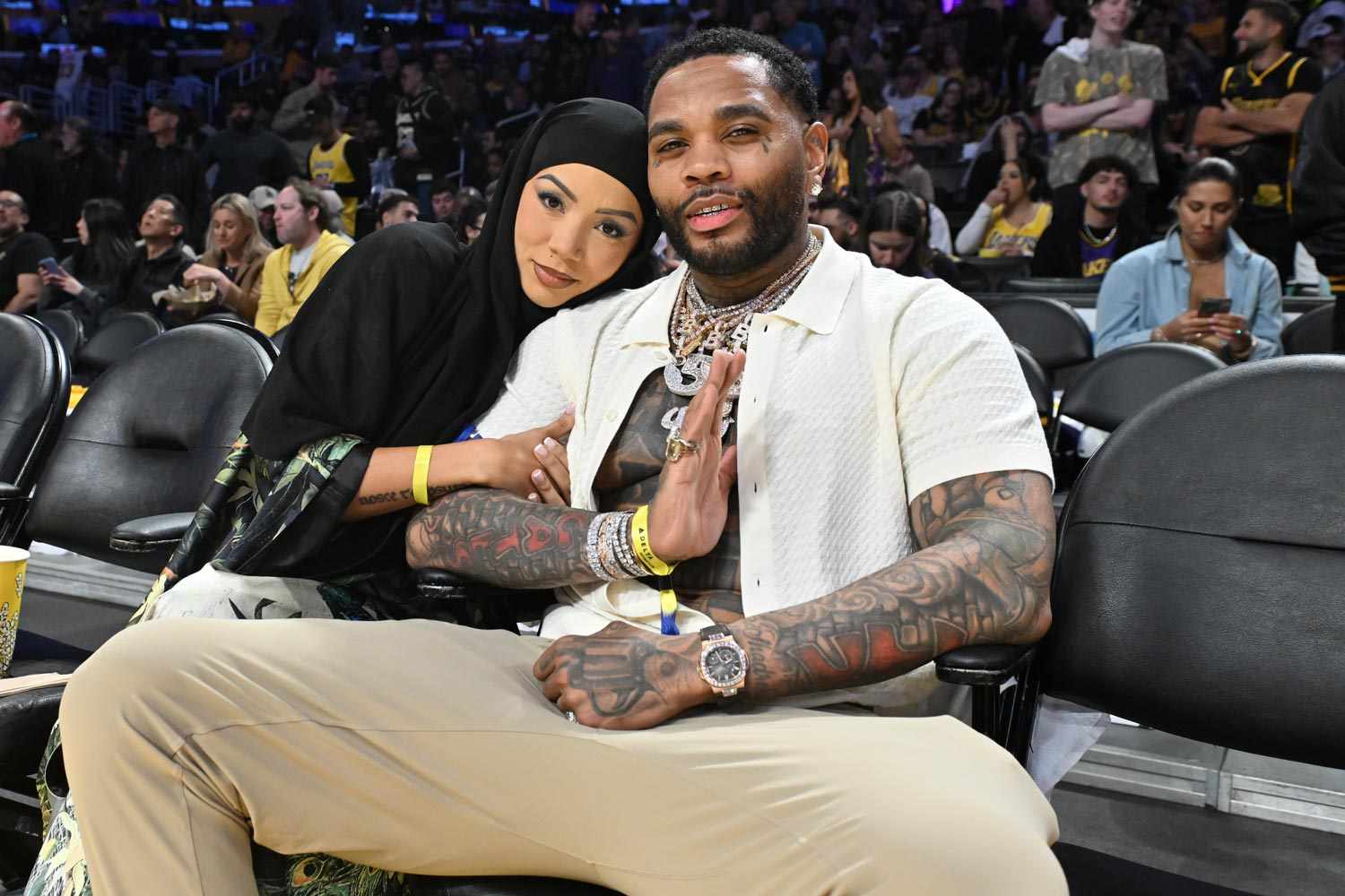 Kevin Gates sits courtside at an NBA game, dressed casually and enjoying the event.