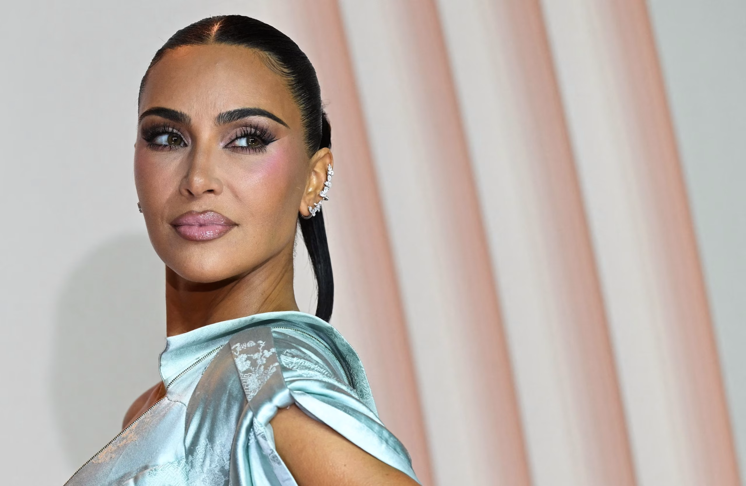 Kim Kardashian wearing a glamorous blue gown on the red carpet, posing confidently for photographers.