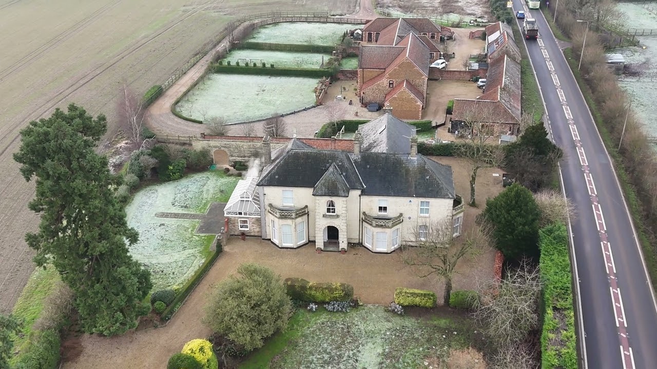Aerial view of Stephen Fry’s countryside home in West Bilney, Norfolk, surrounded by gardens and open fields.