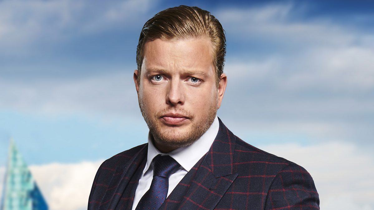 Tom Skinner posing confidently for the camera on the set of The Apprentice, wearing a sharp suit and displaying his trademark smile.