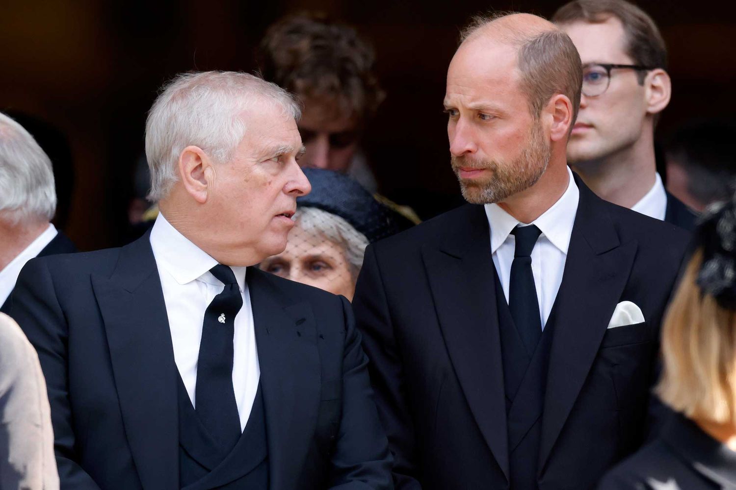 Prince Andrew reaching out to Prince William, who appears unresponsive, during a public event.