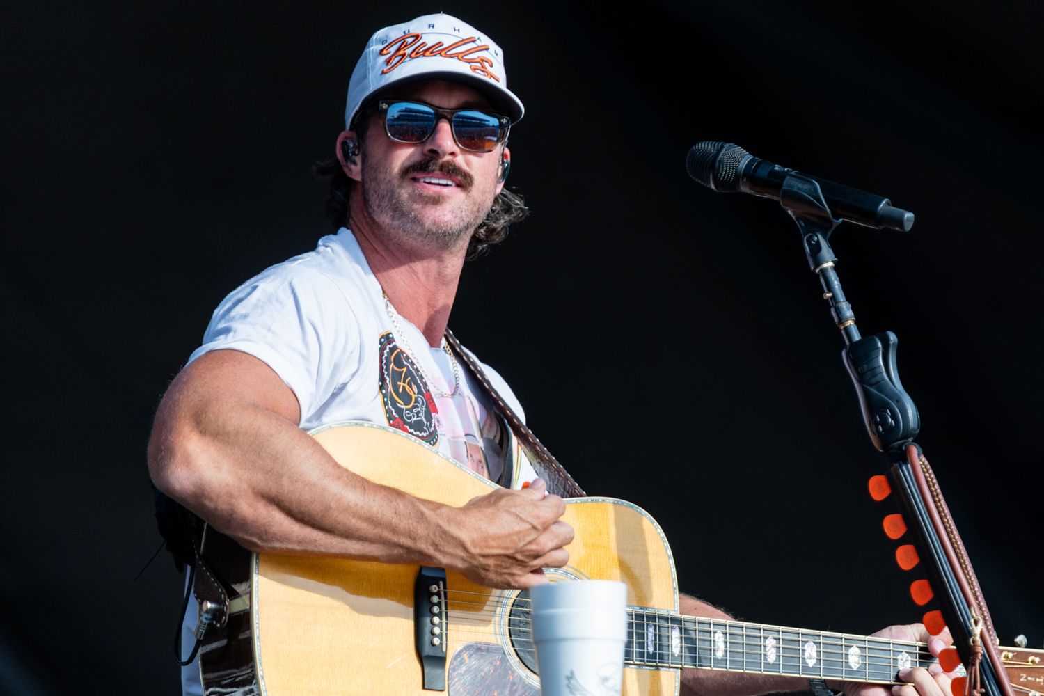 Riley Green smiling at the crowd during a live performance.