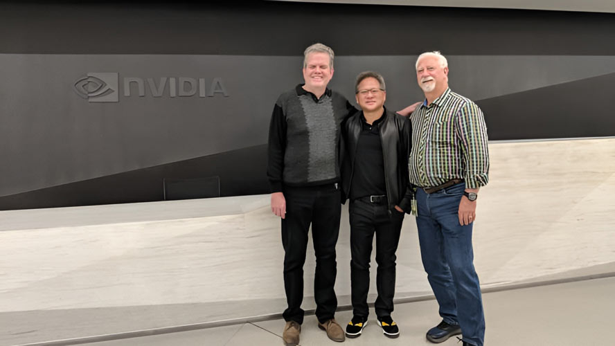 Jensen Huang, Chris Malachowsky, and Curtis Priem standing together in front of an NVIDIA sign, smiling for the camera.