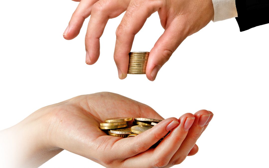 One hand passing coins to another hand, symbolizing wealth transfer.