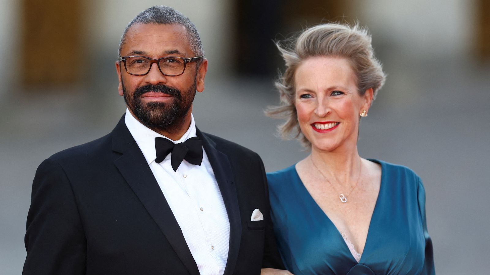 James Cleverly standing next to his wife, both smiling and dressed elegantly