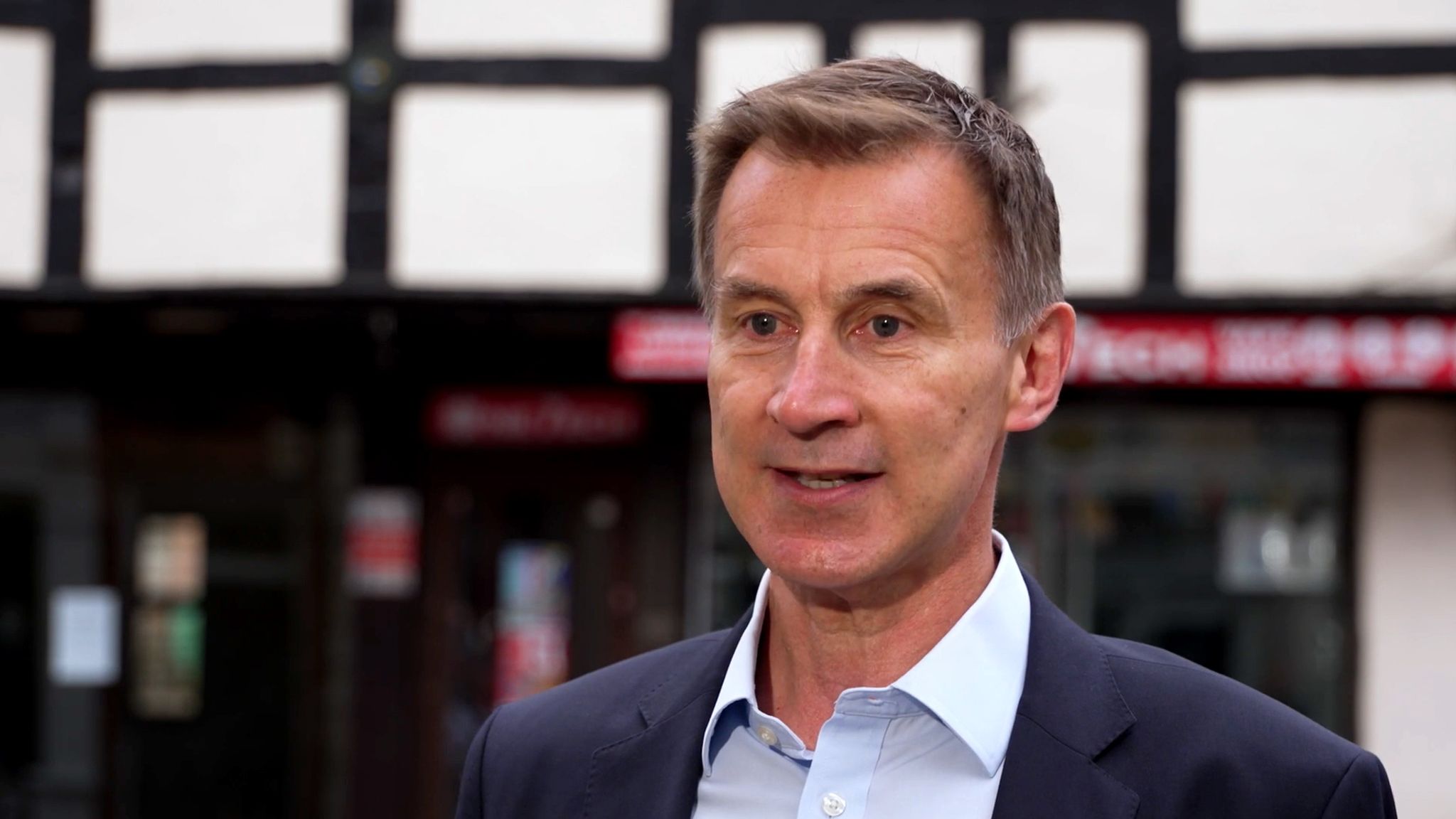 Jeremy Hunt speaking to reporters outside, giving an interview to Sky News with microphones in front of him.