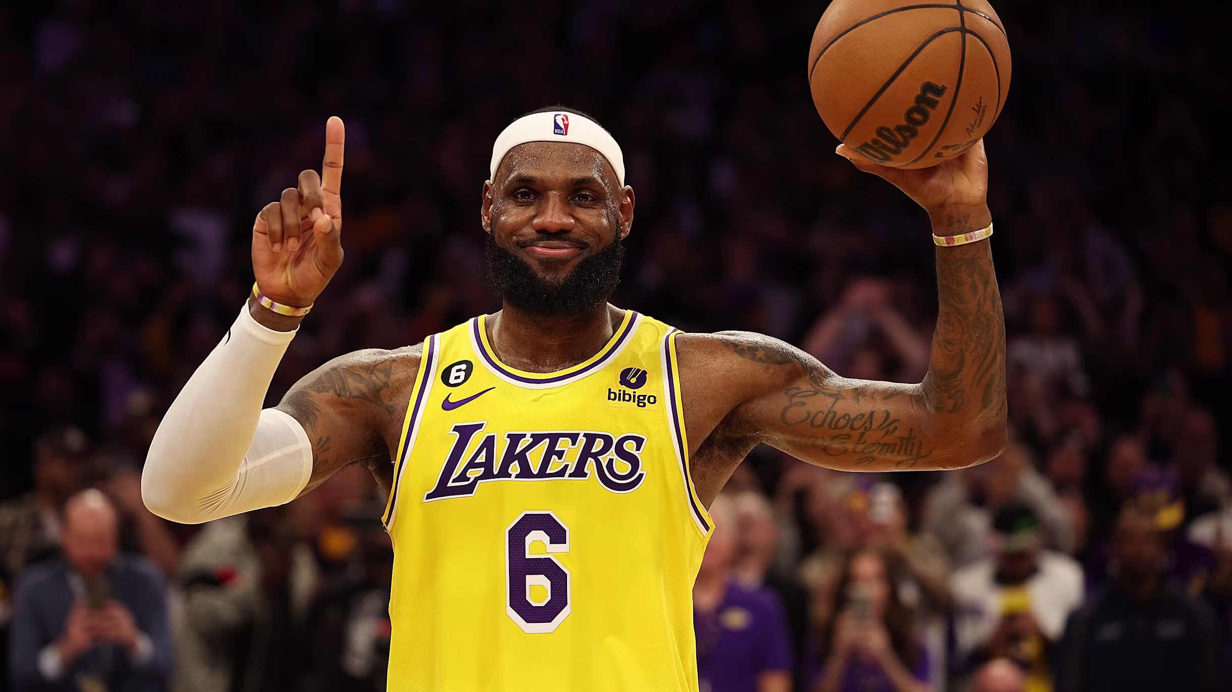 LeBron James holding a basketball in one hand and raising one finger in celebration.