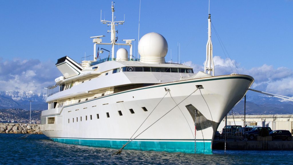 "The Kingdom 5KR superyacht docked at a marina, formerly the Trump Princess and Adnan Khashoggi's Nabila, a symbol of billionaire wealth and global financial power.