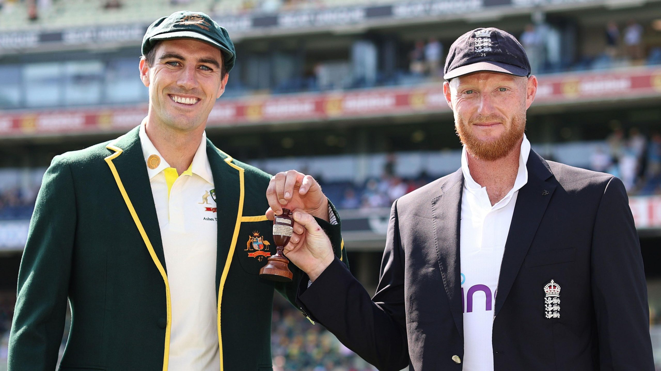 Players from both England and Australia standing together in formal team attire, jointly holding the Ashes urn ahead of the first Test, symbolising the tradition and commercial significance of the series.