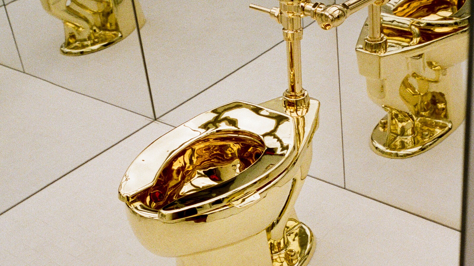 A gleaming 18-karat gold toilet, sculpted by Maurizio Cattelan, displayed on a pedestal; symbolizing both luxury art and Ripley’s Believe It or Not!’s $12.1M acquisition.