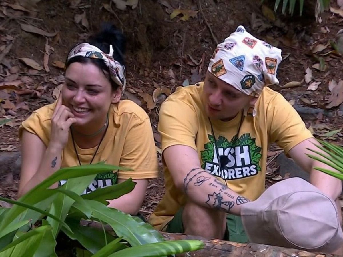 Shona McGarty and Aitch sitting close together in the jungle, smiling and laughing during a break from I’m A Celebrity 2025.