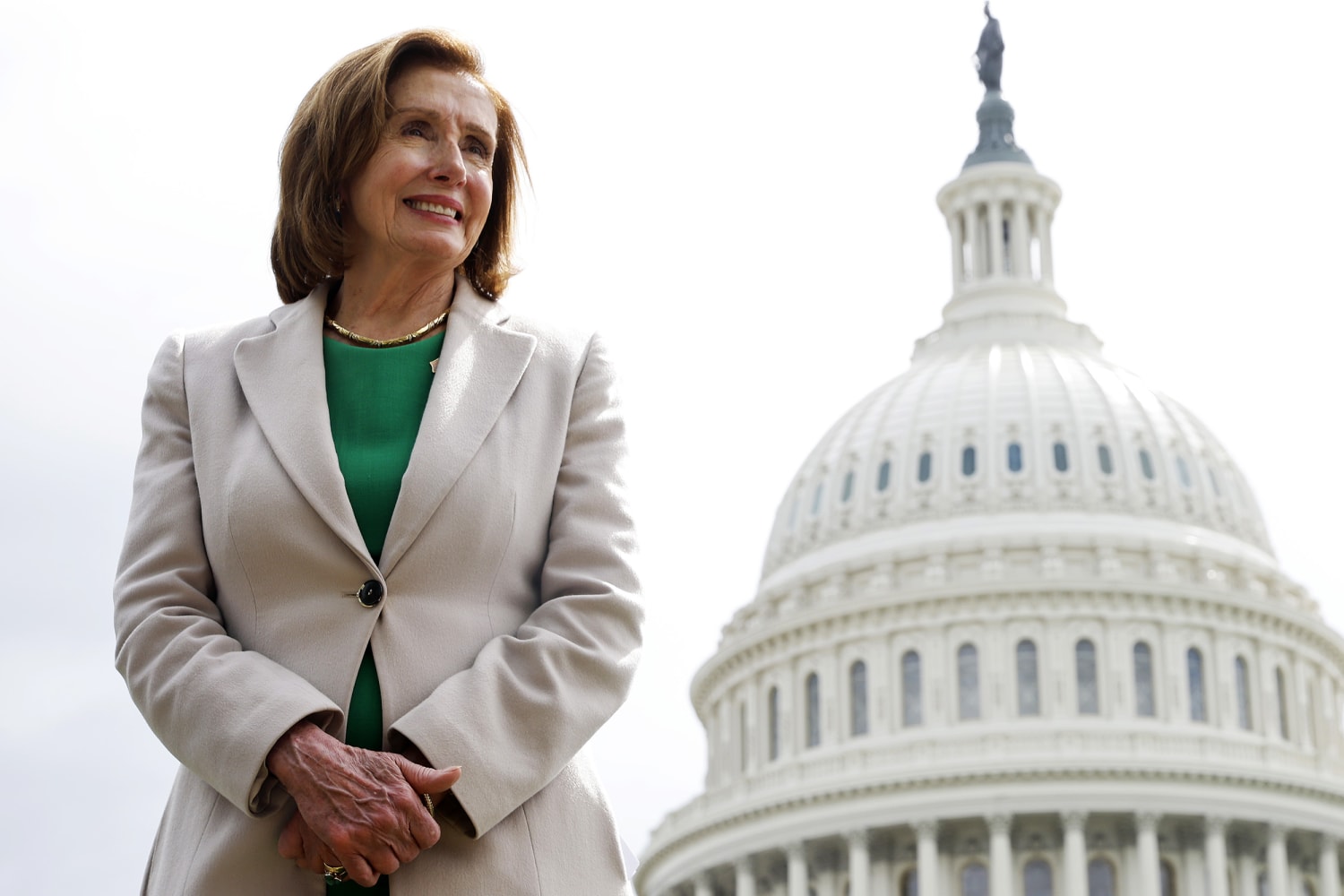 Nancy Pelosi standing in front of the U.S. Capitol, looking poised and confident.