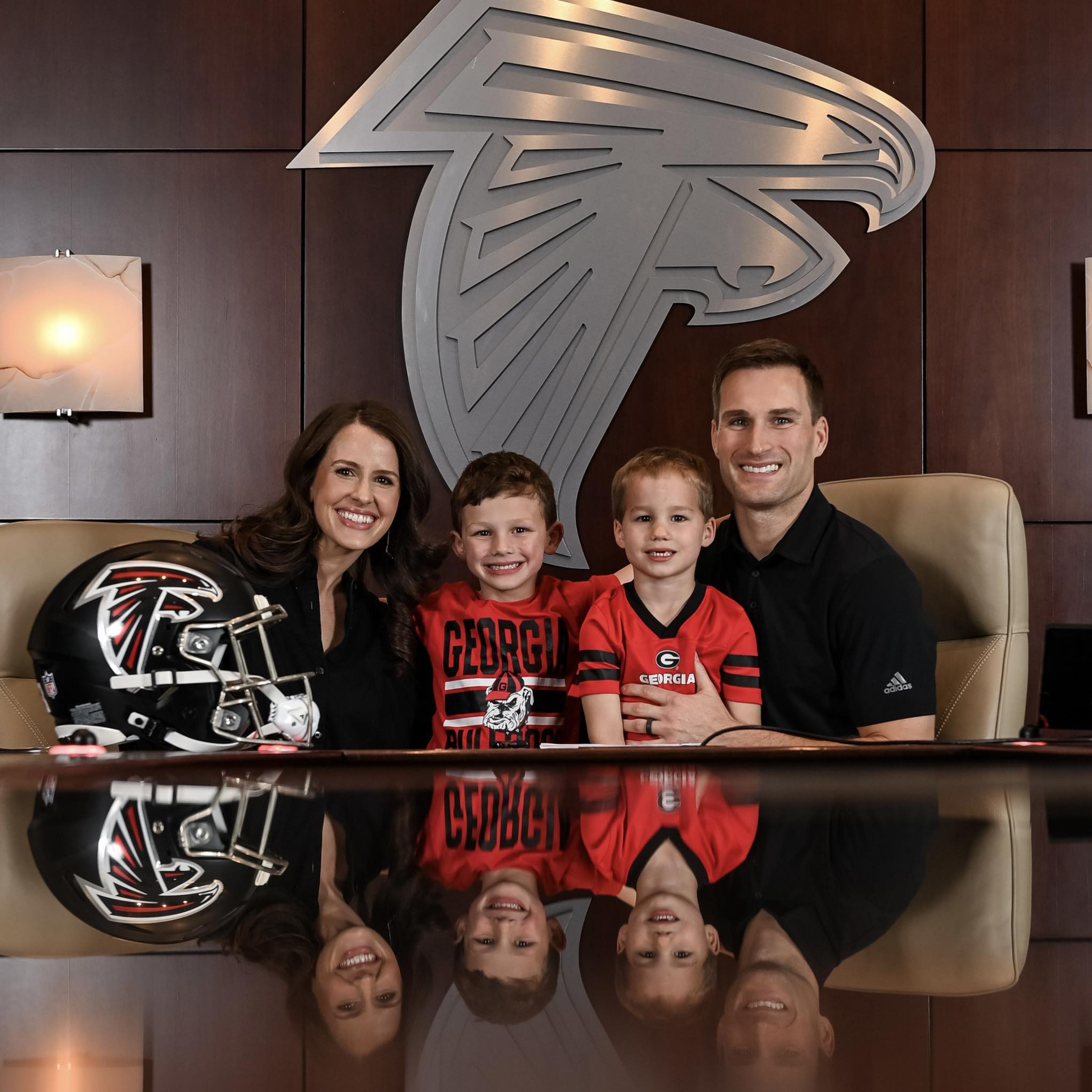Kirk Cousins posing with his wife and children while signing his contract with the Atlanta Falcons.
