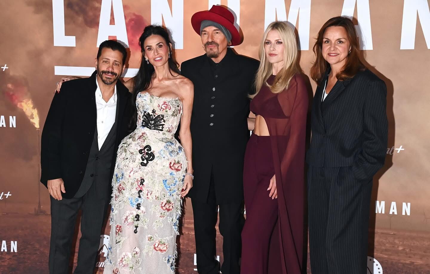 Ali Larter poses with her Landman Season 2 co-stars on the London premiere red carpet, wearing a sheer burgundy bralette and cape, smiling confidently alongside the cast.
