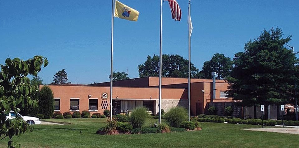 The exterior of FCI Fort Dix federal prison in New Jersey, showing the facility’s fences and guard towers under a blue sky.