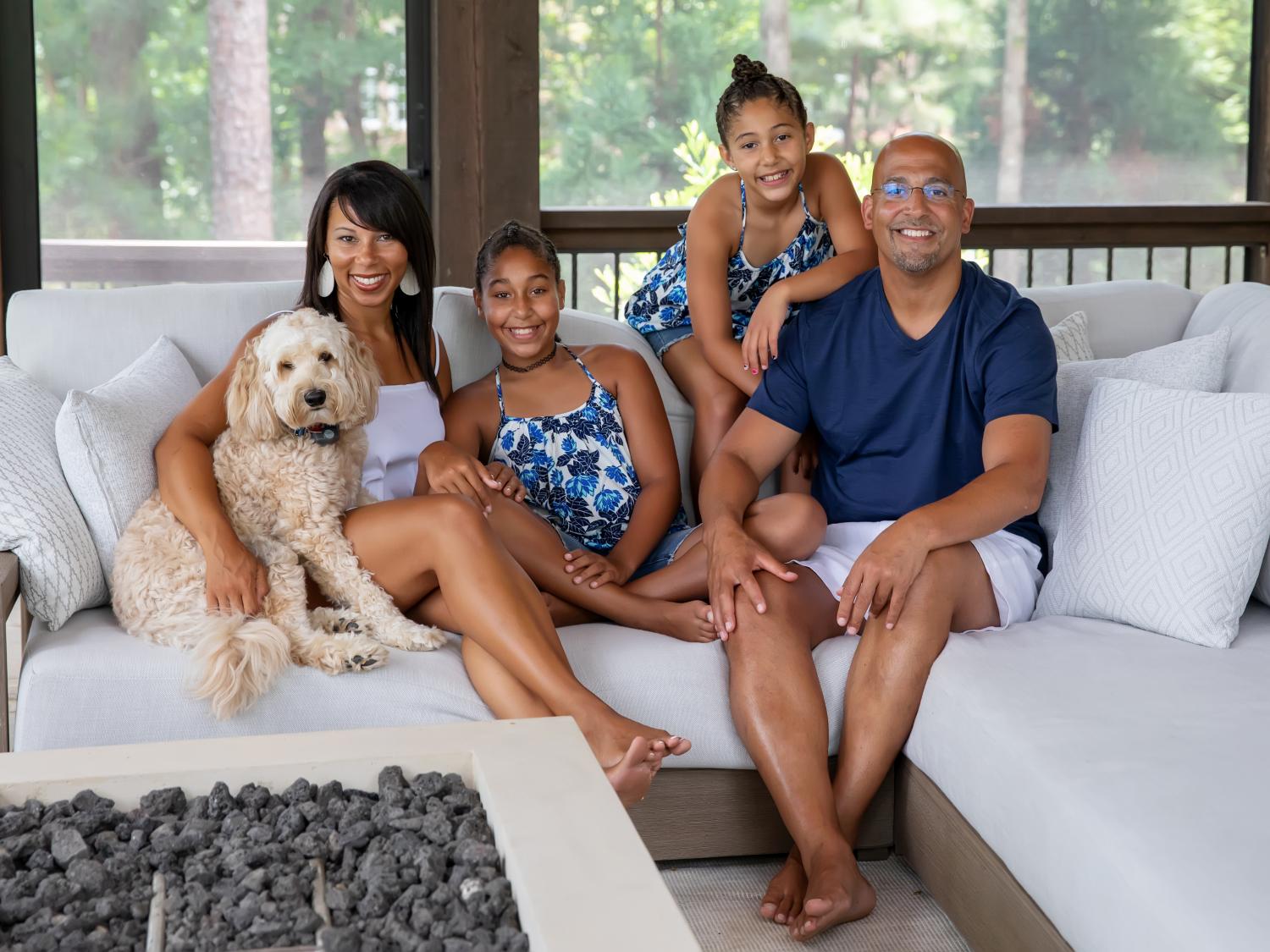James Franklin and his family at home with their dog, relaxed and smiling.