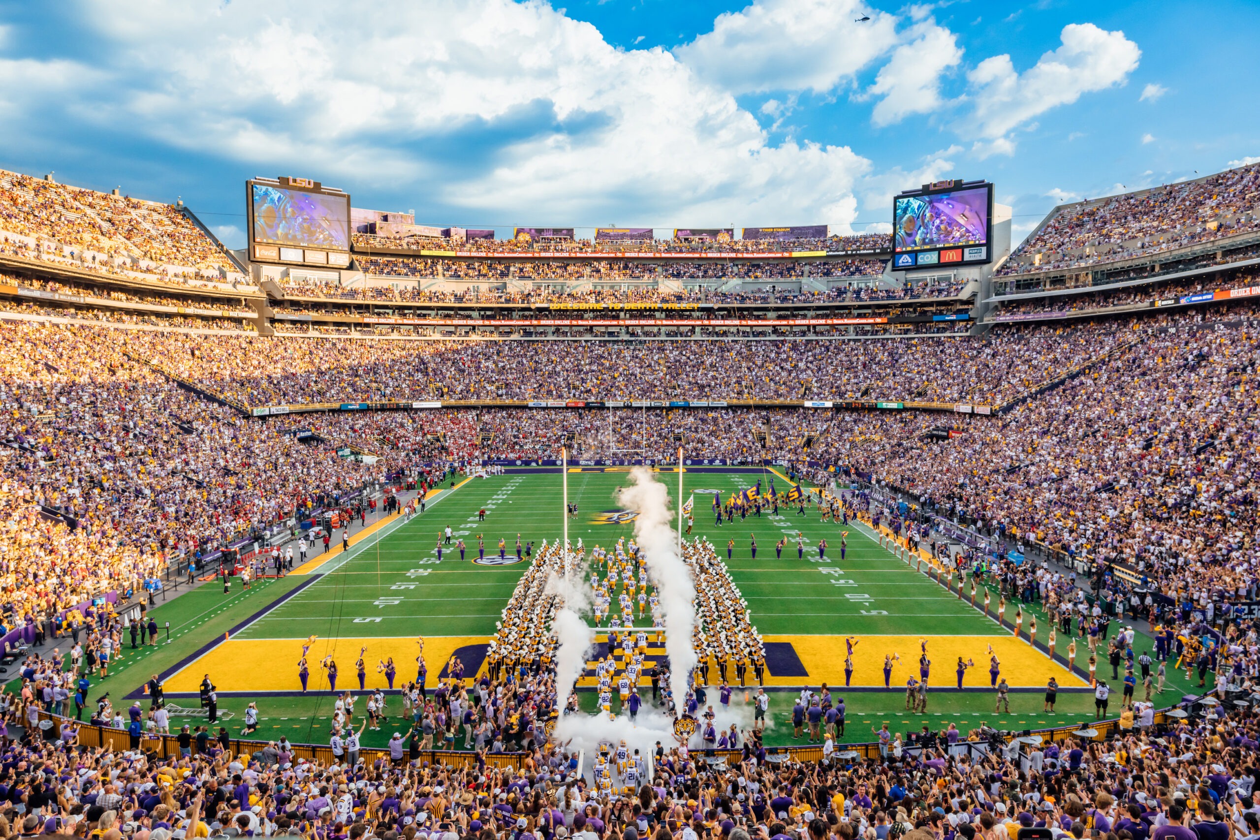 Aerial view of Tiger Stadium in Baton Rouge, Louisiana, filled with fans and team colors during a game, showcasing the iconic structure and vibrant atmosphere of LSU football.