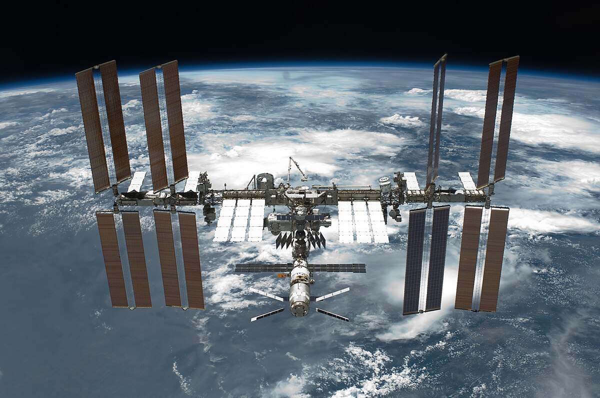 The International Space Station orbiting above Earth with solar panels extended against the blackness of space.