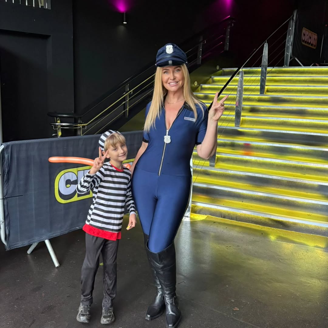 Josie Gibson dressed in a police-inspired catsuit posing with her son Reggie, who is wearing a prisoner outfit, celebrating Halloween 2025.