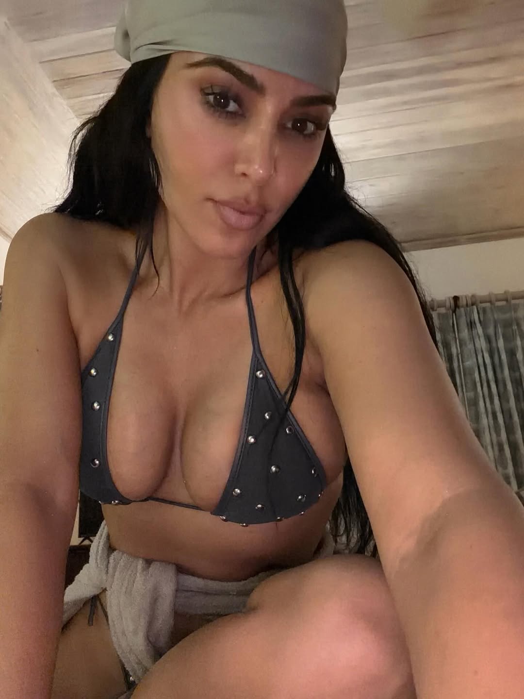 Kim Kardashian posing in a black two-piece bikini at a sun-drenched resort, celebrating her sister’s birthday.