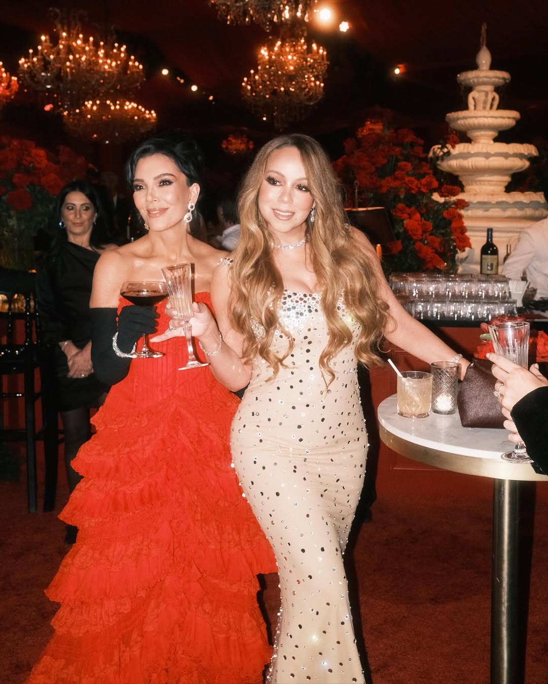 Kris Jenner and Mariah Carey pose together at Jenner’s 70th birthday party, both dazzling in glamorous gowns as they toast to the Bond-themed celebration.