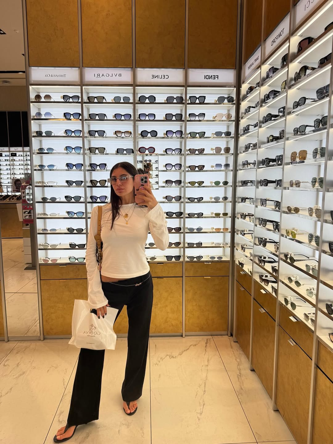 Layla Al-Momani posing inside a sunglasses store, casually chic in shades, from the same Instagram post where she revealed her engagement ring.