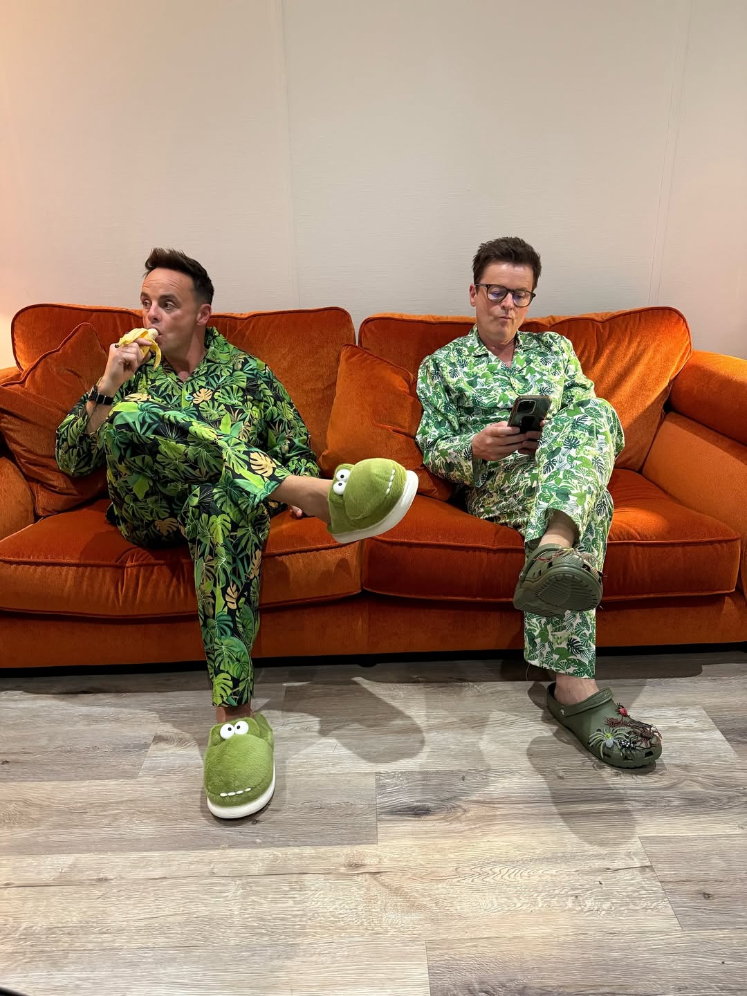 Ant and Dec relax in matching jungle-themed pyjamas, with Ant wearing crocodile slippers and Dec in insect-adorned green crocs, ahead of the 2025 I’m A Celebrity… Get Me Out of Here! series.