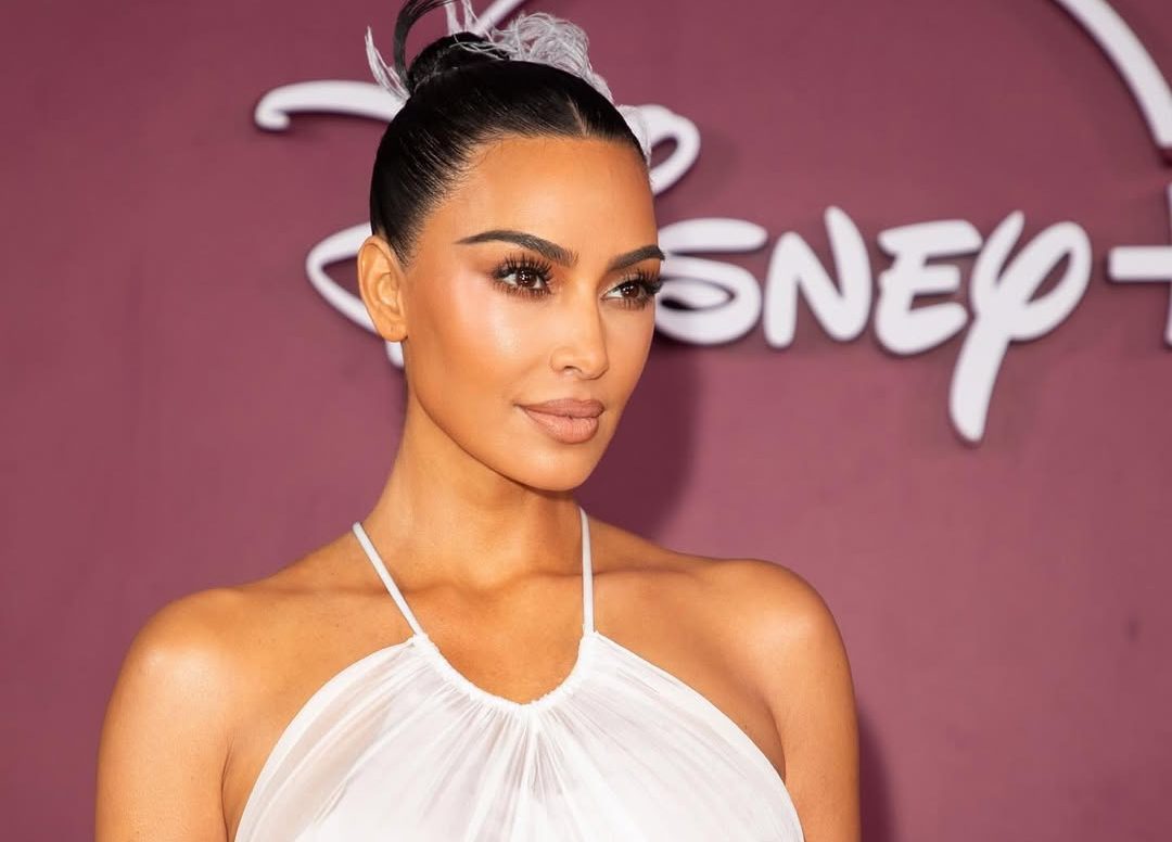 Kim Kardashian on the red carpet in Rio de Janeiro, wearing a daring backless gown with feathered details and side cut-outs, posing confidently for photographers.