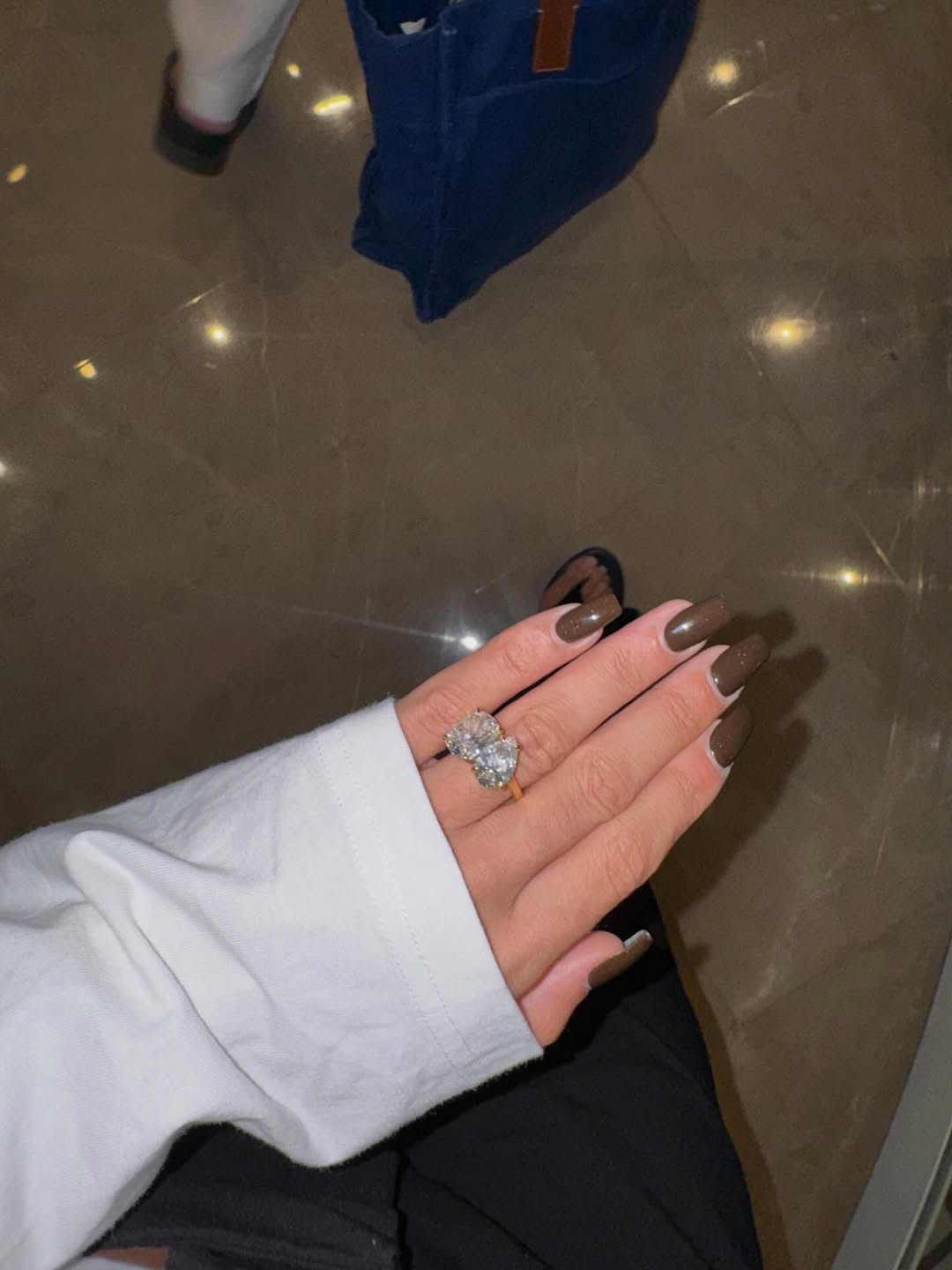 Close-up of Layla Al-Momani’s teardrop and square-cut diamond engagement ring on a gold band, highlighting its size and intricate design.