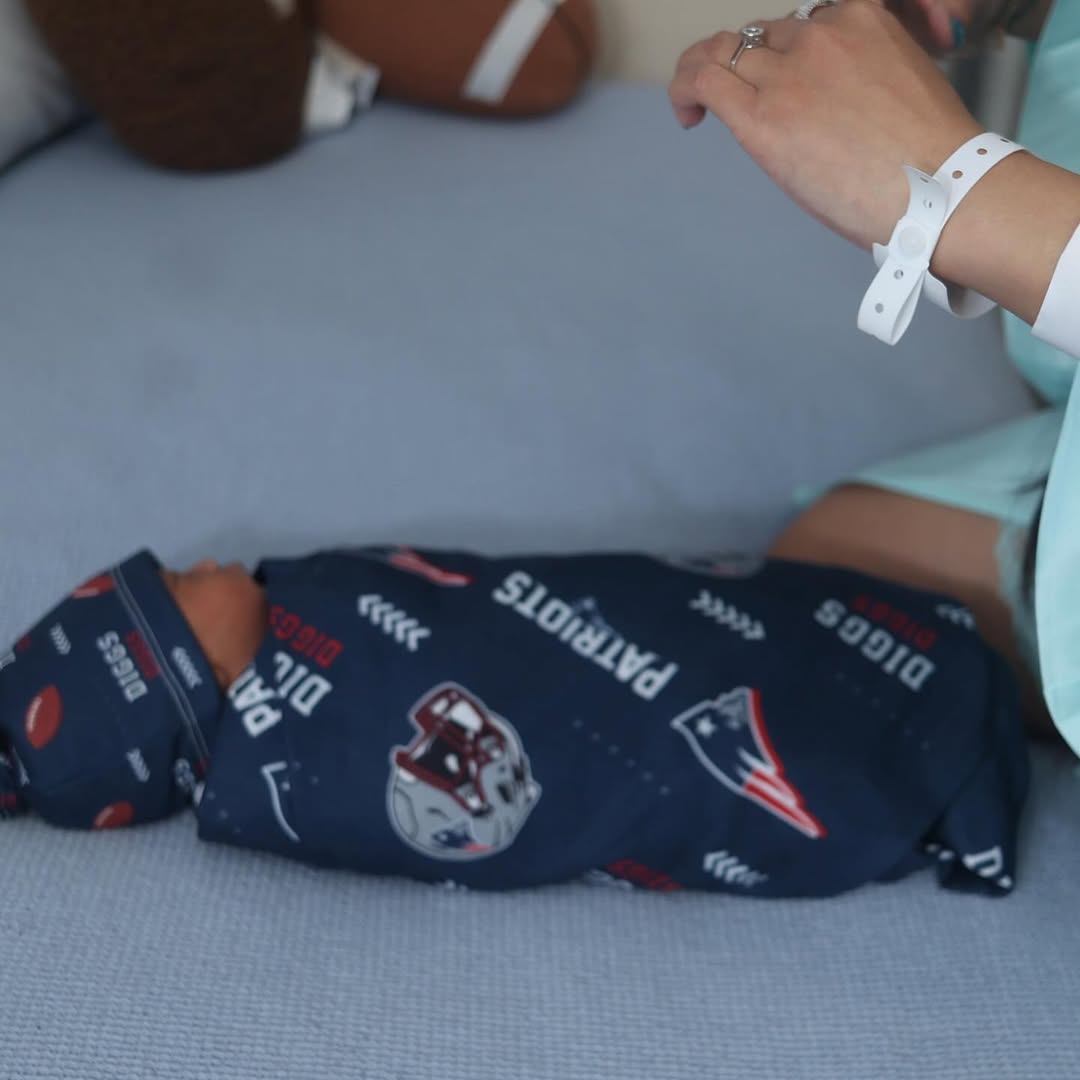 Cardi B’s hand resting above her newborn son, prominently displaying a sparkling diamond ring on her wedding finger.