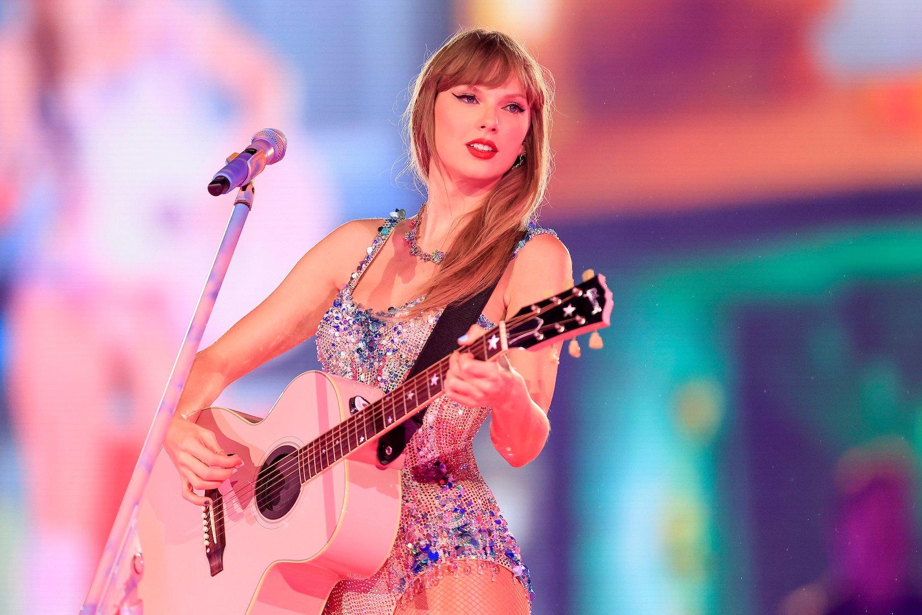Taylor Swift performing on stage during the Eras Tour, holding her guitar, captivating the audience as she prepares for the Disney docuseries capturing her historic tour finale.