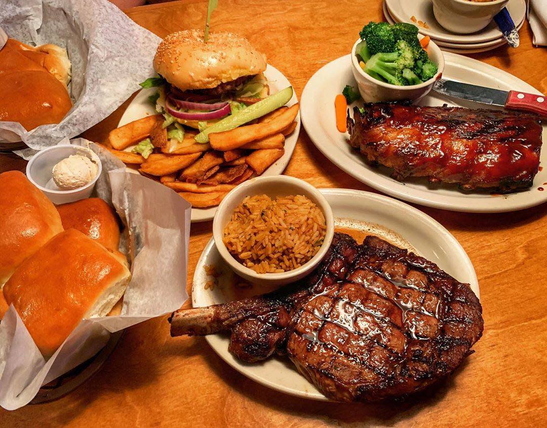 A table overflowing with sizzling steaks, ribs, sides, and bread at Texas Roadhouse.