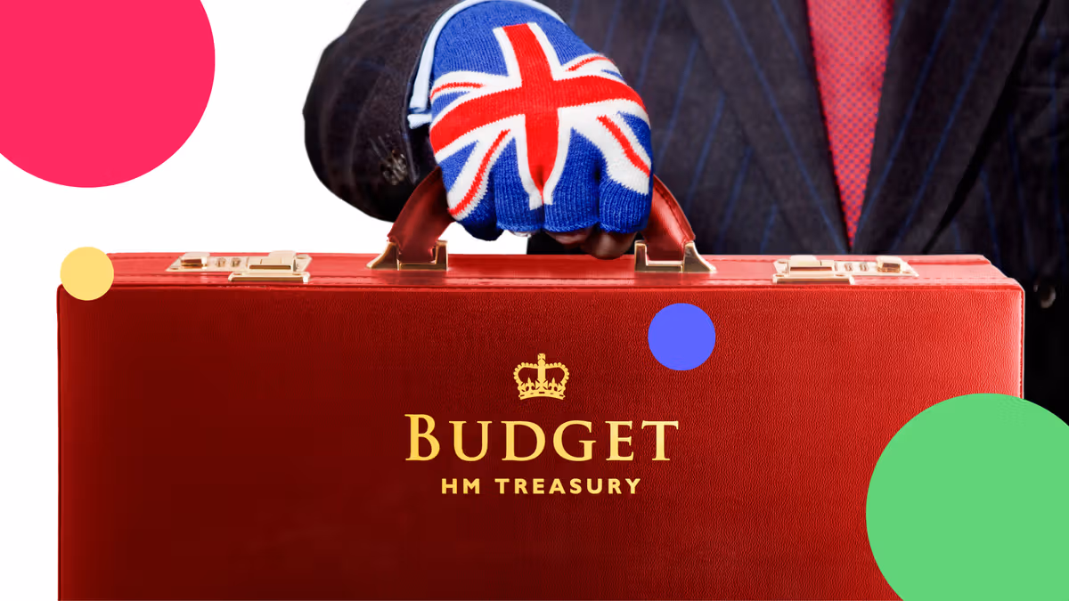 A gloved hand wearing a Union Jack glove holds the iconic red HM Treasury Budget box, symbolizing the UK government’s financial plans.
