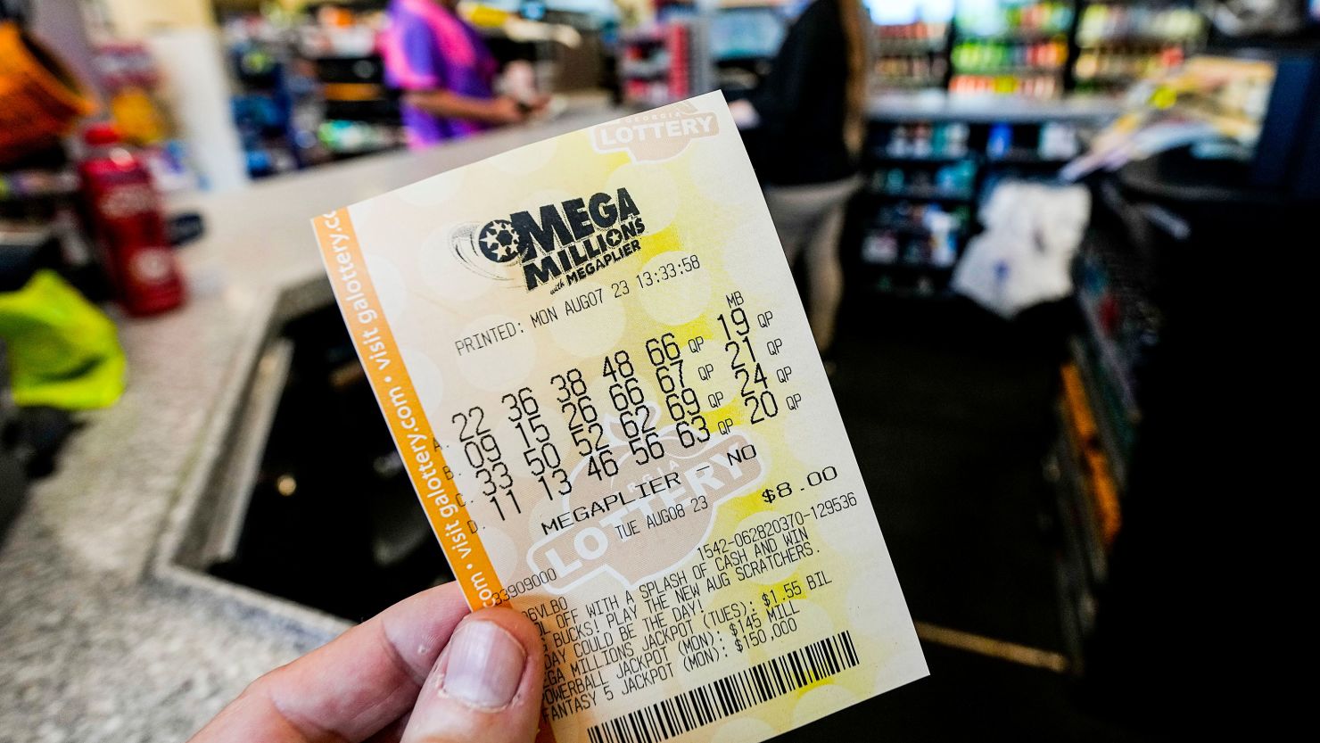 Close-up of a person's hand clutching a winning Mega Millions lottery ticket, fingers gripping the edge tightly in anticipation, with colorful numbers and Mega Ball printed on the slip against a blurred background.