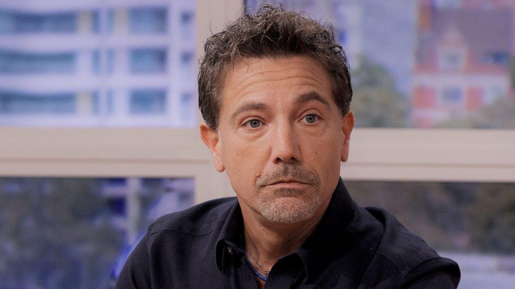 Gino D’Acampo looking downcast and somber, reflecting the personal and professional challenges he faces amid bullying allegations and lost TV contracts.