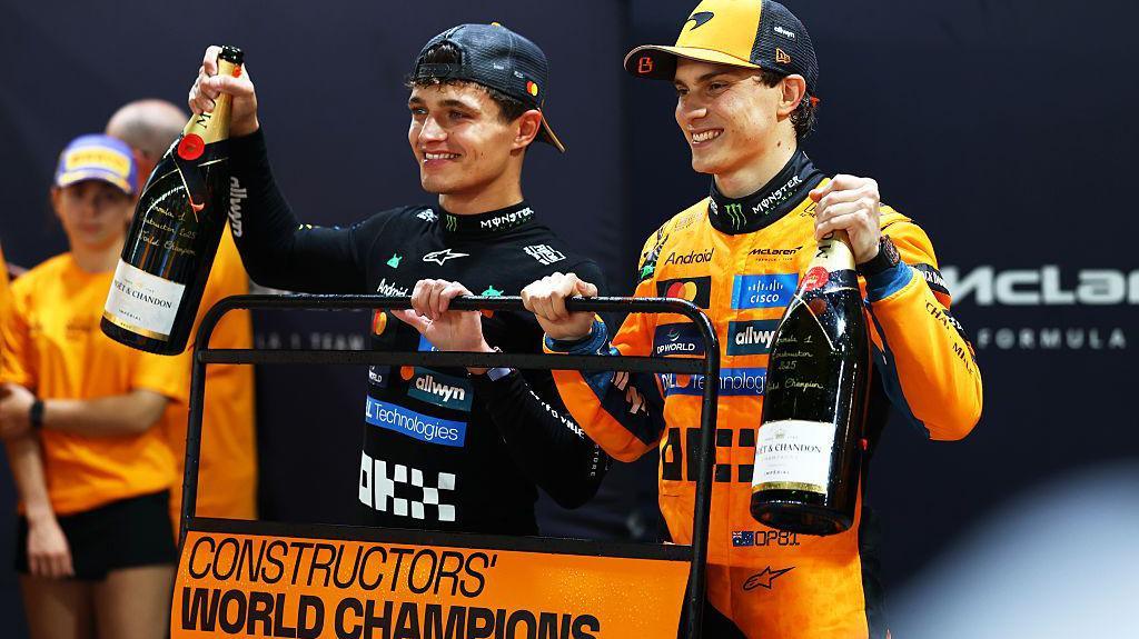 Lando Norris and Oscar Piastri celebrating on the podium after a successful Grand Prix finish.