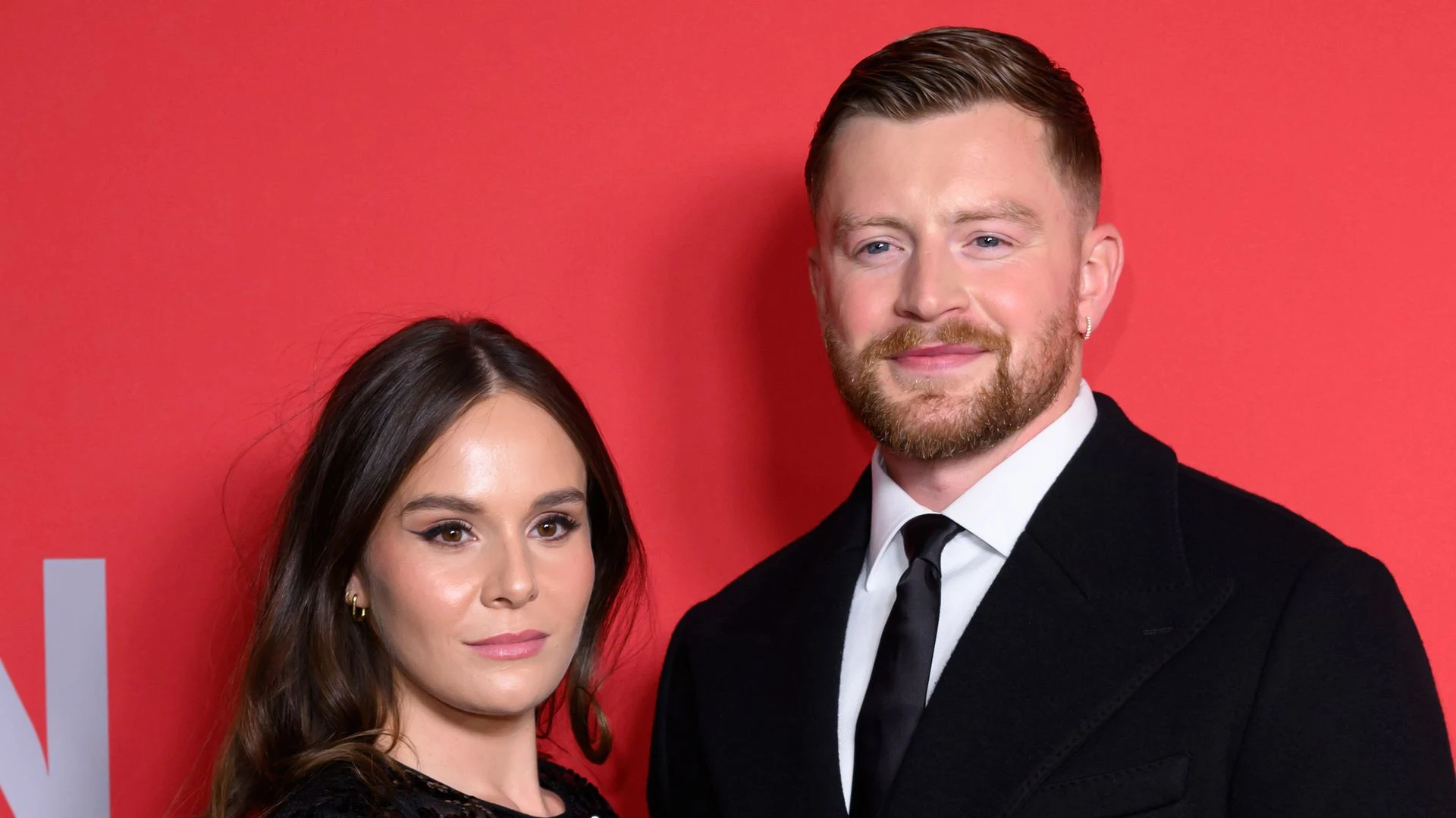 Adam Peaty and Holly Ramsay smiling together on the red carpet, dressed in formal evening attire.
