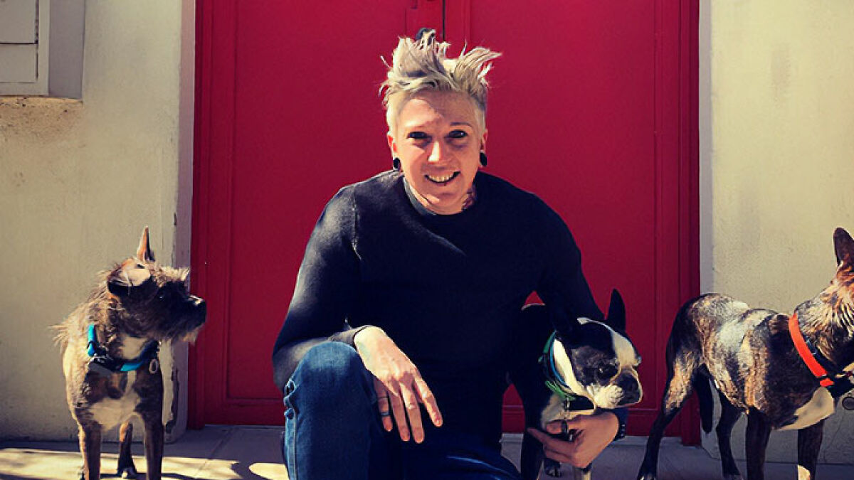 Mynie Steffens smiling while sitting with her three dogs, looking happy and relaxed.