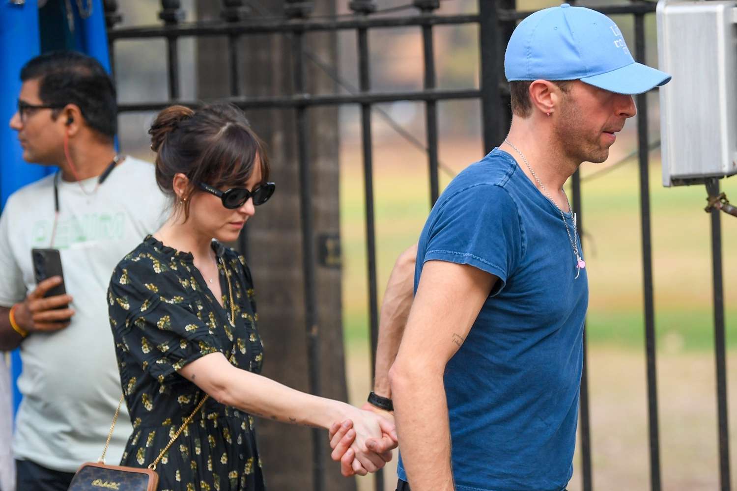 Dakota Johnson and Chris Martin holding hands while avoiding the camera.