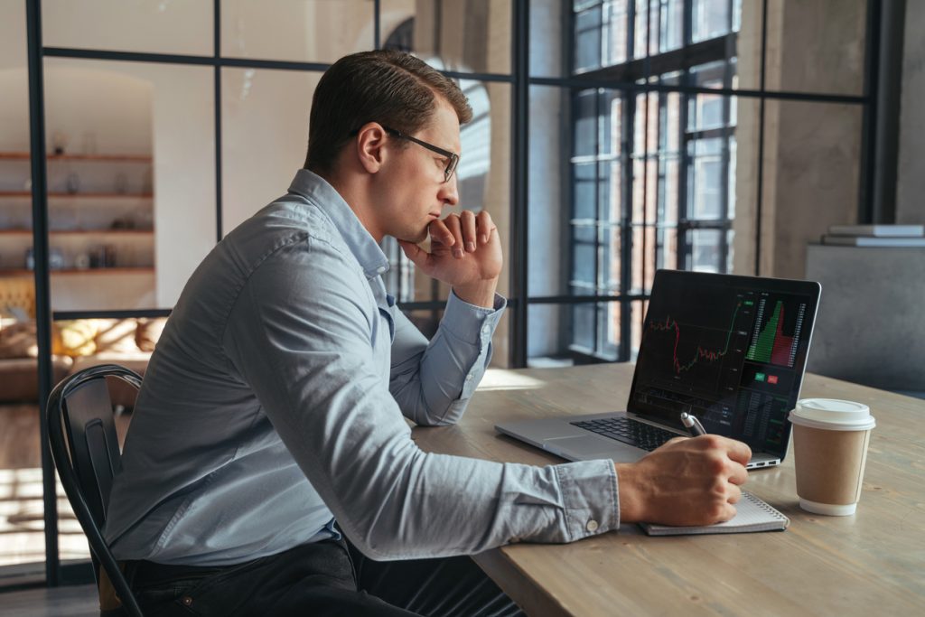 serious crypto trader analyzing risks of buying cryptocurrency in global recession looking at chart