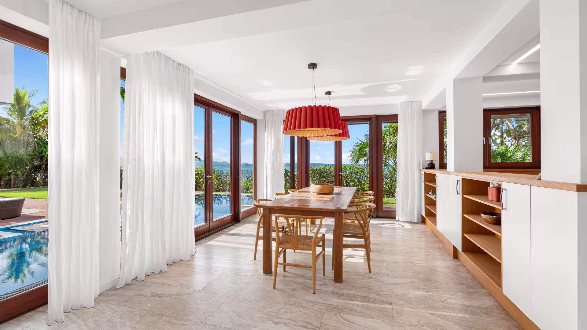 Interior view of the dining area in Chuck Norris’ Anguilla villa, featuring an open-plan layout, large windows overlooking the ocean, and elegant seating.