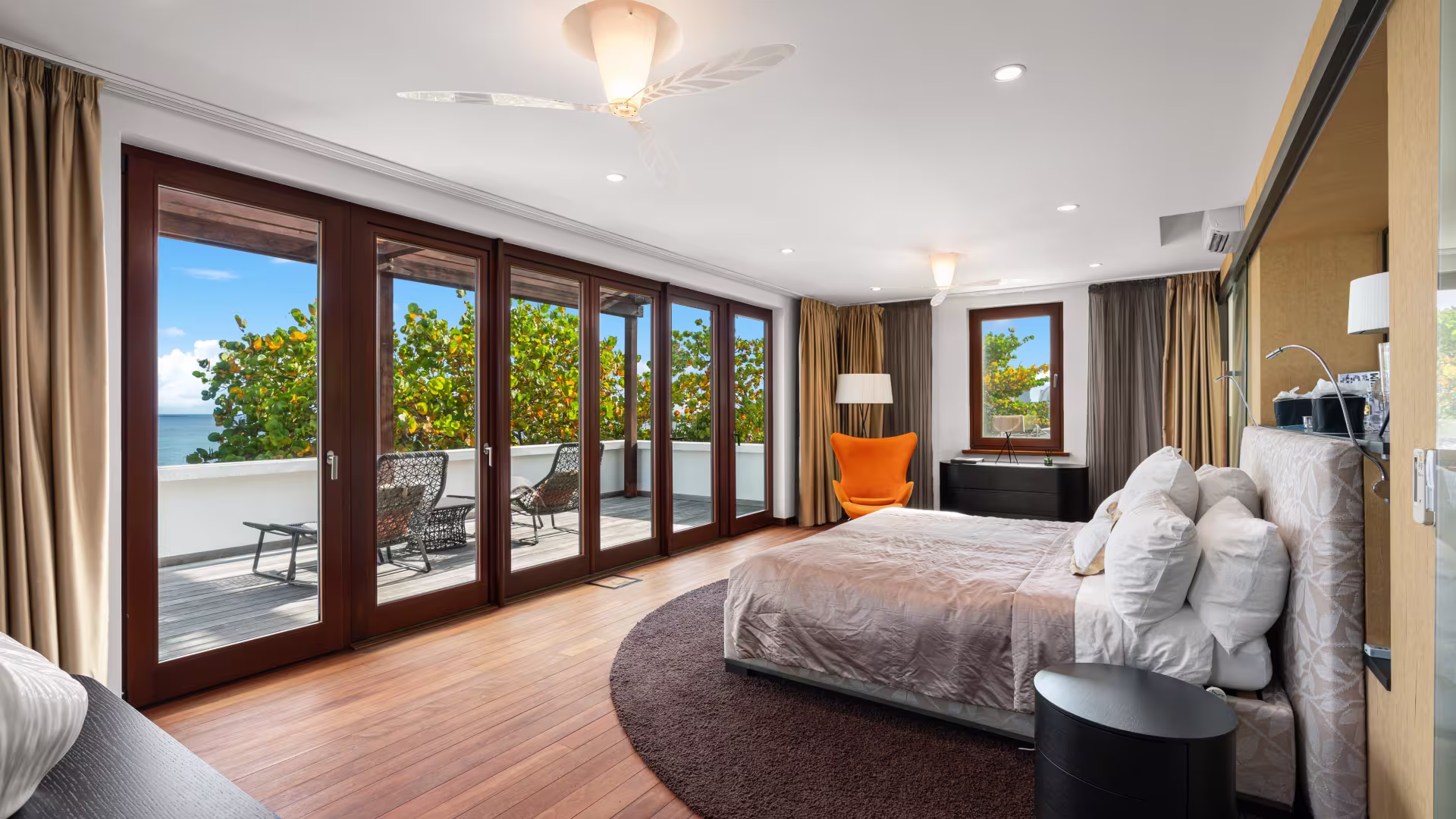 Interior view of the master bedroom in Chuck Norris’ Anguilla villa, featuring large windows with ocean views, elegant décor, and a spacious layout.