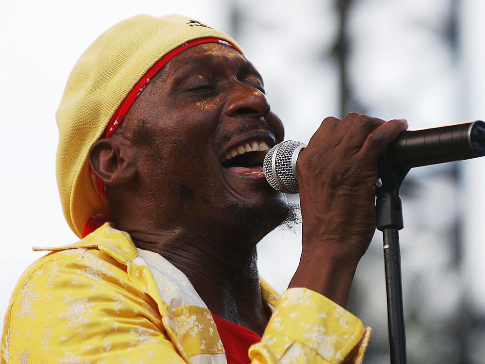 Jimmy Cliff smiling while performing at an outdoor music festival, engaging with the audience.