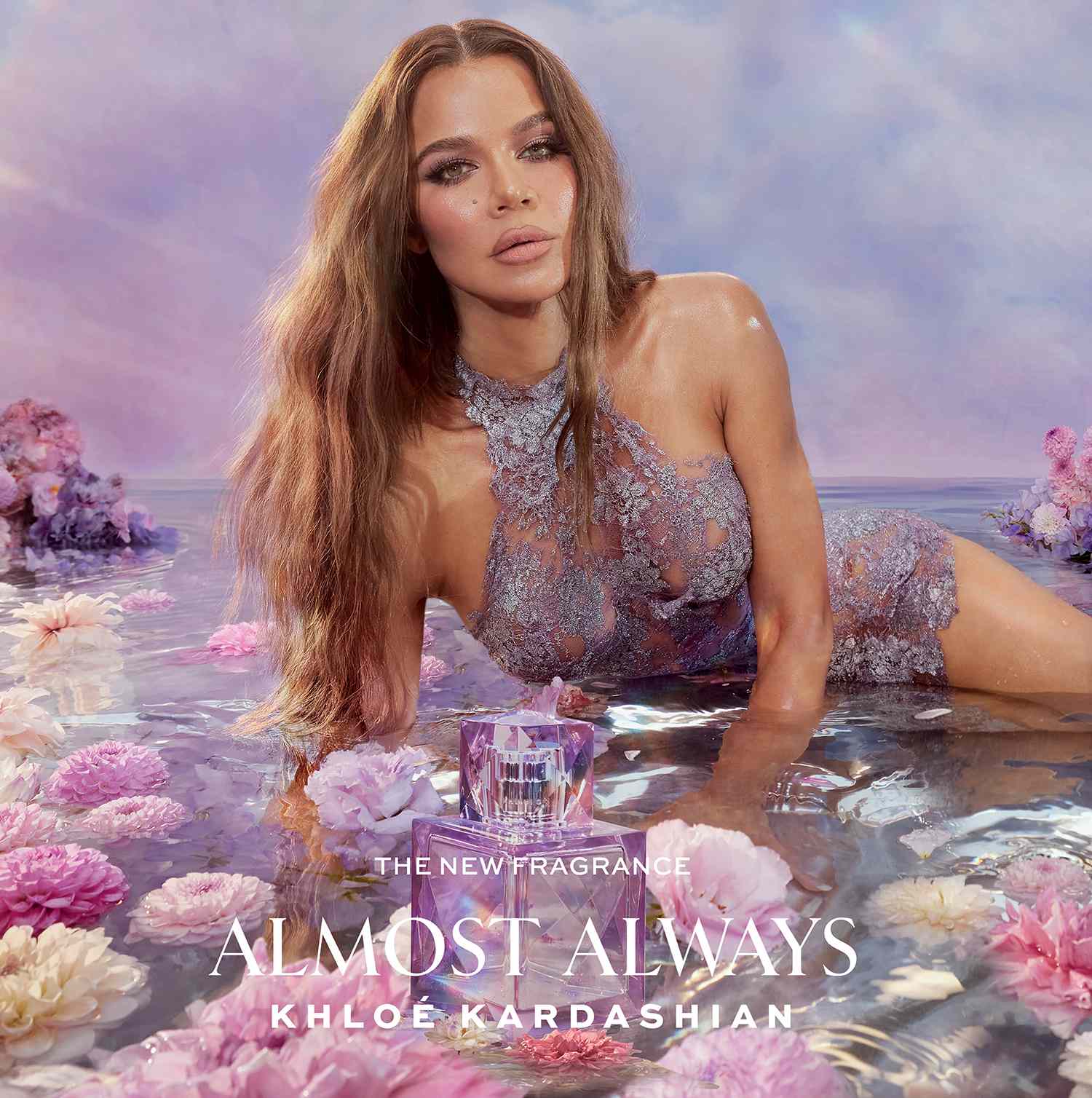 Khloé Kardashian lying in shallow water for her fragrance poster, with the perfume bottle displayed nearby.