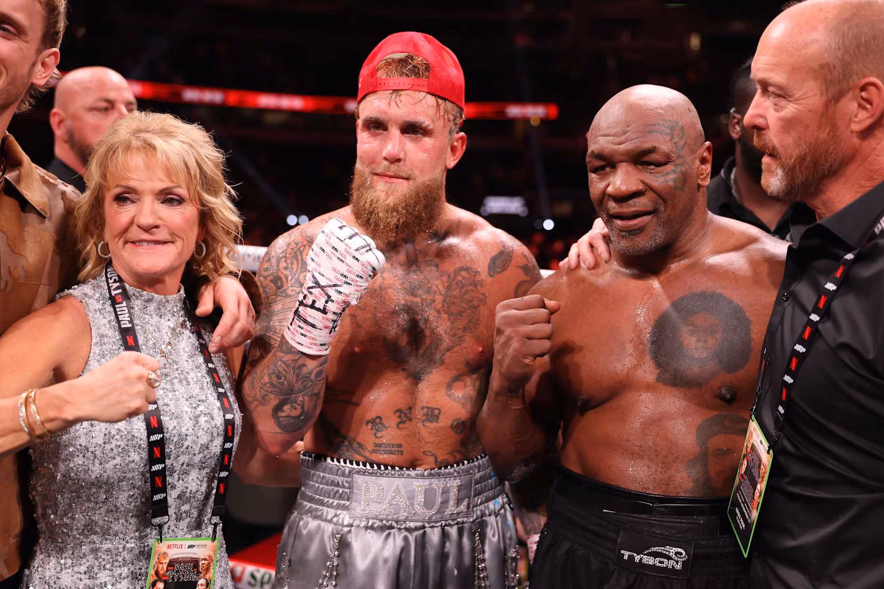 Jake Paul and Mike Tyson posing together after their 2024 exhibition fight, both smiling and wearing boxing attire in the ring.