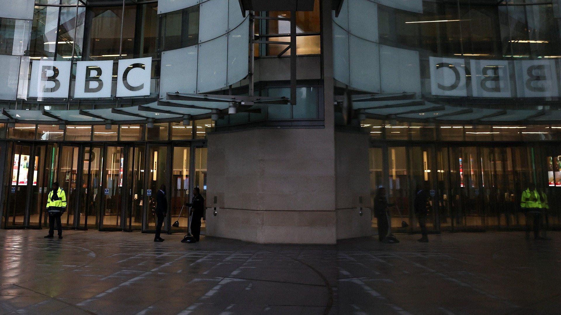 The main entrance of the BBC headquarters in London, featuring the iconic glass façade and the large BBC logo above the doorway.