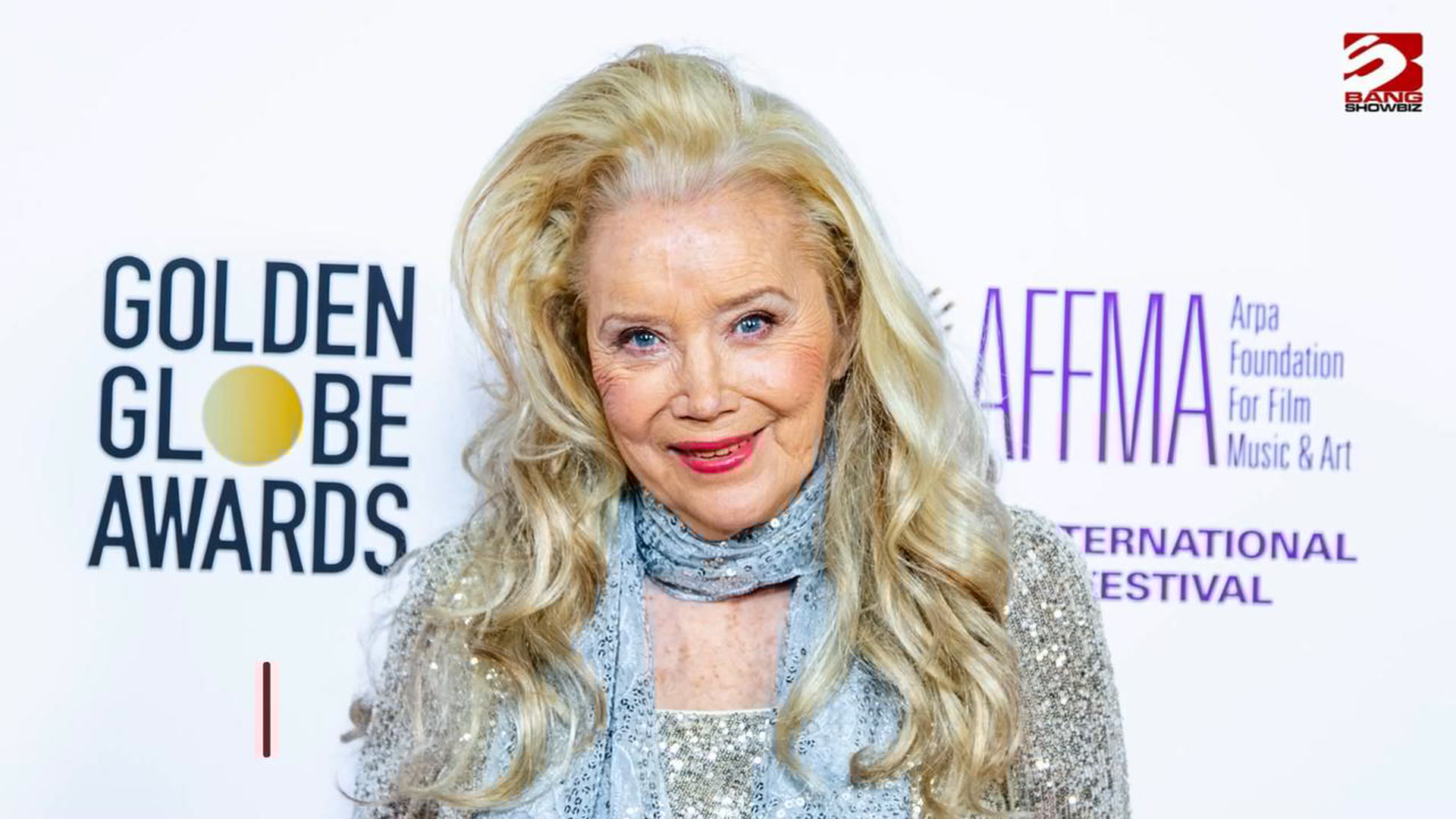 Sally Kirkland smiling and posing on the red carpet at a recent event, wearing an elegant gown.